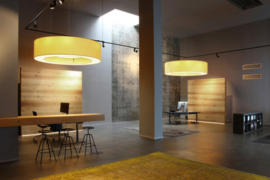 Modernes Arbeitszimmer ohne Kamin mit Arbeitsplatz, grauer Wandfarbe, Betonboden, freistehendem Schreibtisch, grauem Boden und Tapetenwänden in Köln