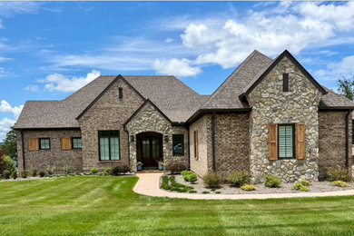 Example of a transitional two-story brick house exterior design in Other with a brown roof