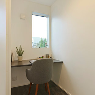Modern home office and library with painted wood flooring, a built-in desk and green floors.