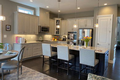 Eat-in kitchen - traditional l-shaped dark wood floor and brown floor eat-in kitchen idea in DC Metro with a double-bowl sink, raised-panel cabinets, white cabinets, white backsplash, ceramic backsplash, stainless steel appliances, an island and white countertops