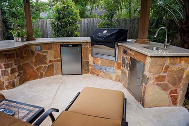 Mid-sized traditional backyard patio in Houston with an outdoor kitchen, natural stone pavers and a pergola.