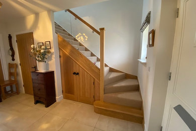 Photo of a medium sized contemporary wood l-shaped glass railing staircase in Hampshire with wood risers and brick walls.