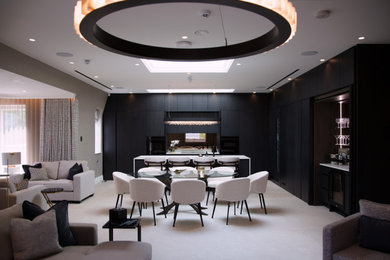 This is an example of a large contemporary l-shaped open plan kitchen in Other with a submerged sink, flat-panel cabinets, black cabinets, quartz worktops, metallic splashback, mirror splashback, black appliances, an island, grey floors, white worktops and a vaulted ceiling.