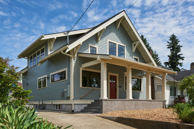 Photo of a mid-sized arts and crafts two-storey blue exterior in Portland with vinyl siding, a hip roof and a shingle roof.