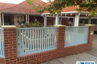 Brick boundary fence with piers and wooden slats