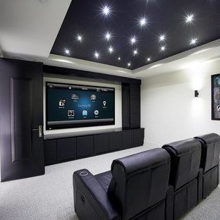 Photo of a large contemporary home cinema in Sussex with multi-coloured walls, carpet and a projector screen.