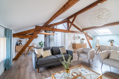 Cette photo montre un salon nature ouvert avec un mur bleu, un sol en bois brun, un sol marron, poutres apparentes et un plafond voûté.