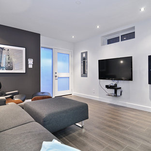 This is an example of a contemporary open plan home cinema in Vancouver with white walls, laminate floors and a wall mounted tv.