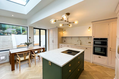 Inspiration for a mid-sized contemporary single-wall eat-in kitchen in London with a drop-in sink, recessed-panel cabinets, pink cabinets, marble benchtops, white splashback, marble splashback, coloured appliances, light hardwood floors, with island, white benchtop and recessed.