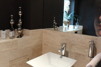 Design ideas for a medium sized contemporary cloakroom with a wall mounted toilet, beige tiles, limestone tiles, black walls, limestone flooring, a wall-mounted sink and beige floors.
