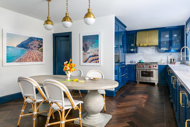 Beach style u-shaped dark wood floor and brown floor eat-in kitchen photo in San Francisco with glass-front cabinets, blue cabinets, marble countertops, white backsplash, marble backsplash, stainless steel appliances and white countertops