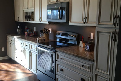Example of a mid-sized transitional l-shaped dark wood floor and brown floor kitchen design in Cincinnati with raised-panel cabinets, beige cabinets, granite countertops and stainless steel appliances