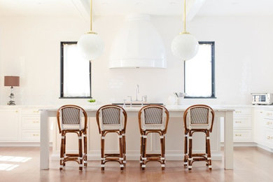 Inspiration for a large transitional l-shaped medium tone wood floor eat-in kitchen remodel in Chicago with a farmhouse sink, recessed-panel cabinets, white cabinets, marble countertops, white backsplash, glass tile backsplash, stainless steel appliances and an island