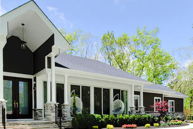 Example of a transitional one-story stone house exterior design in New York with a black roof