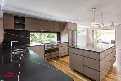 Inspiration for a modern kitchen in Brisbane with an undermount sink, beige cabinets, granite benchtops, black splashback, stainless steel appliances, light hardwood floors and with island.