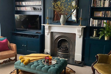 ロンドンにある高級な中くらいなエクレクティックスタイルのおしゃれなリビング (カーペット敷き、標準型暖炉、石材の暖炉まわり、壁掛け型テレビ、ベージュの床、青い壁) の写真