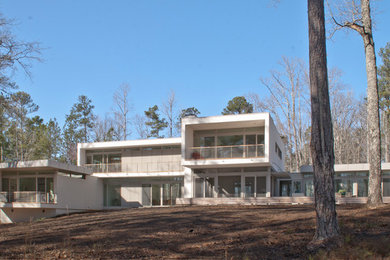 Example of a mid-sized minimalist white two-story stucco exterior home design in Atlanta with a mixed material roof