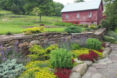 Photo of a large farmhouse full sun backyard stone retaining wall landscape in Boston.