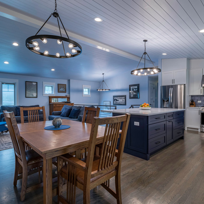 Example of a transitional medium tone wood floor, brown floor, vaulted ceiling and wainscoting kitchen/dining room combo design in Chicago with blue walls and no fireplace