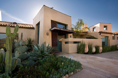 This is an example of a large one-storey adobe beige house exterior in Santa Barbara with a flat roof and a tile roof.