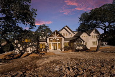 Inspiration for a farmhouse gray two-story stone and board and batten house exterior remodel in Austin with a shingle roof and a black roof