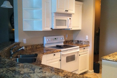 Open concept kitchen - mid-sized transitional porcelain tile open concept kitchen idea in Other with a double-bowl sink, raised-panel cabinets, white cabinets, granite countertops, multicolored backsplash, white appliances and an island