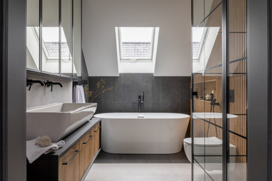 Example of a large trendy master black tile single-sink, vaulted ceiling and wood wall bathroom design in San Francisco with recessed-panel cabinets, light wood cabinets, a one-piece toilet, a vessel sink, concrete countertops, gray countertops and a floating vanity