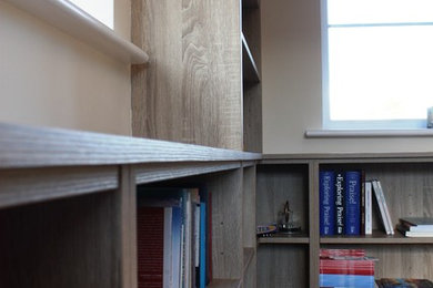This is an example of a medium sized contemporary study in Kent with beige walls, carpet, a freestanding desk and brown floors.