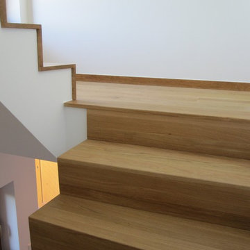 Zweigeschossige, halbgewendelte Betontreppe mit Eiche Leimholzplatte belegt und