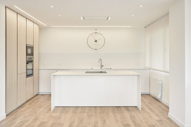 Ejemplo de cocinas en L contemporánea de tamaño medio abierta con fregadero bajoencimera, armarios con paneles lisos, puertas de armario de madera clara, electrodomésticos de acero inoxidable, suelo de madera en tonos medios y una isla