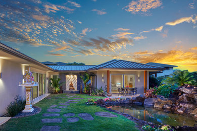Contemporary stucco house exterior in Hawaii with a hip roof and a metal roof.