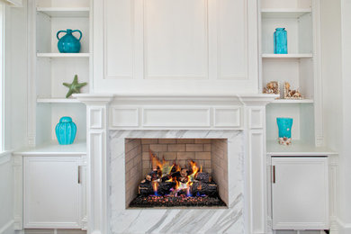 Inspiration for a mid-sized timeless dark wood floor and brown floor living room remodel in Miami with white walls, a standard fireplace, a stone fireplace and no tv