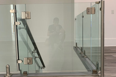 Ejemplo de escalera recta minimalista pequeña con barandilla de vidrio