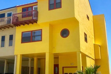ヒューストンにあるビーチスタイルのおしゃれな家の外観 (漆喰サイディング、黄色い外壁) の写真