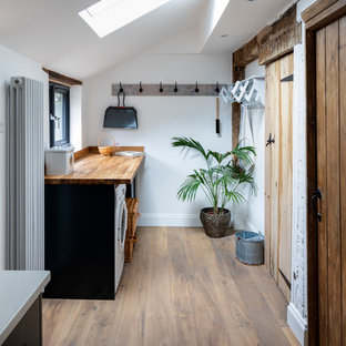 Inspiration för små lantliga linjära beige tvättstugor enbart för tvätt, med träbänkskiva, vita väggar, ljust trägolv och beiget golv
