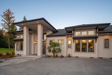 Large tropical white one-story stucco exterior home idea in Portland with a hip roof and a shingle roof