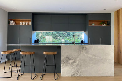 Design ideas for a mid-sized contemporary single-wall eat-in kitchen in Sydney with a double-bowl sink, flat-panel cabinets, marble benchtops, black appliances, light hardwood floors, with island, grey benchtop and grey cabinets.