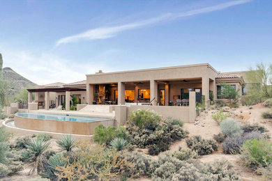 Photo of a large mediterranean one-storey stucco beige house exterior in Phoenix with a hip roof and a tile roof.