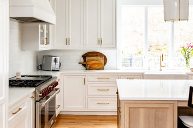 Example of a large transitional medium tone wood floor kitchen design in Boston with shaker cabinets, quartz countertops and an island