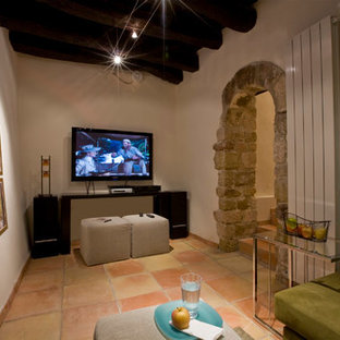 Cette photo montre une salle de cinéma méditerranéenne avec un mur blanc, un sol en carreau de terre cuite, un téléviseur fixé au mur et un sol rouge.