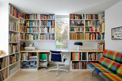 Mid-sized 1950s built-in desk light wood floor and beige floor home office library photo in Grand Rapids with white walls