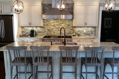 Inspiration for a large contemporary l-shaped dark wood floor enclosed kitchen remodel in Newark with raised-panel cabinets, beige cabinets, granite countertops, multicolored backsplash, glass tile backsplash, stainless steel appliances and an island