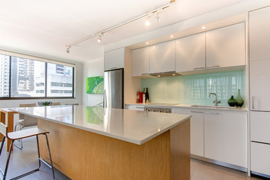 Inspiration for a mid-sized contemporary galley eat-in kitchen in Brisbane with an undermount sink, flat-panel cabinets, white cabinets, quartz benchtops, green splashback, glass sheet splashback, stainless steel appliances, ceramic floors and with island.