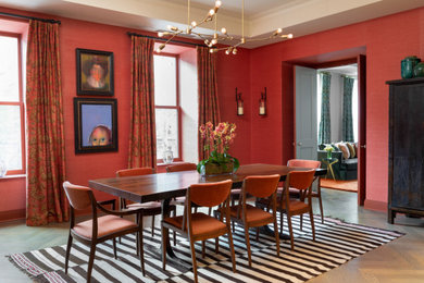 Eclectic dining room in New York with red walls, dark hardwood floors and brown floor.