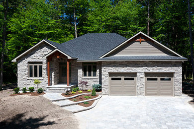 Imagen de fachada de casa gris y gris clásica grande de una planta con revestimiento de hormigón, tejado a cuatro aguas y tejado de teja de madera
