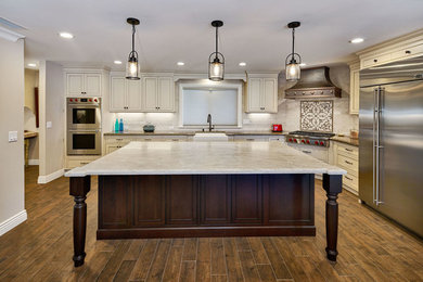 Example of a huge classic l-shaped porcelain tile open concept kitchen design in San Francisco with a farmhouse sink, beaded inset cabinets, white cabinets, granite countertops, brown backsplash, mosaic tile backsplash, stainless steel appliances and an island