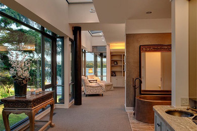 This is an example of an expansive contemporary master bedroom in Seattle with beige walls and carpet.