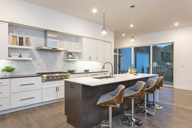 Open concept kitchen - large medium tone wood floor and brown floor open concept kitchen idea in Austin with a double-bowl sink, white cabinets, white backsplash, stainless steel appliances, an island, white countertops, quartz countertops and porcelain backsplash