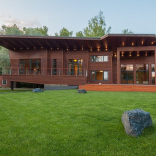 Новый формат декора квартиры: большой, двухэтажный фасад дома коричневого цвета в современном стиле с облицовкой из дерева и односкатной крышей