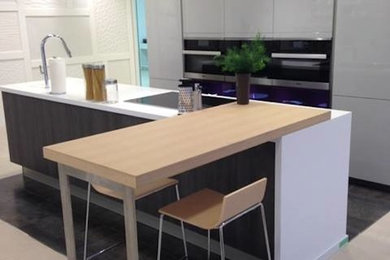 Eat-in kitchen - mid-sized contemporary l-shaped porcelain tile eat-in kitchen idea in Toronto with an undermount sink, flat-panel cabinets, white cabinets, wood countertops, white appliances and an island